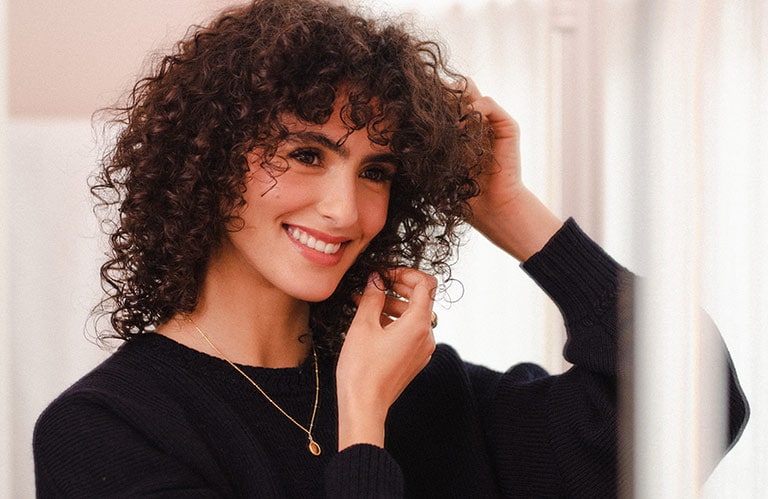 Image of Juny Breeze tending to her curly hair.