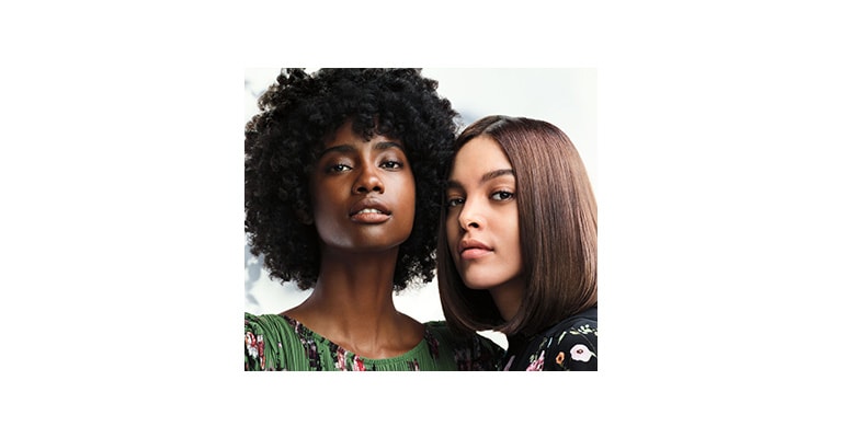 woman with blonde straight hair sitting next to a woman with dark brown straight hair