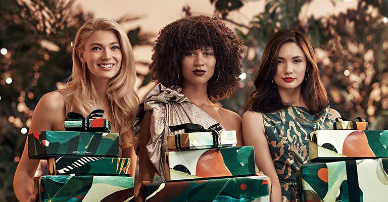 three models holding wrapped gifts