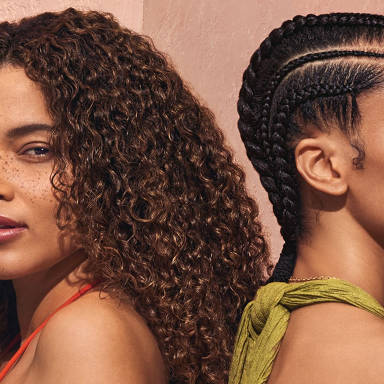 woman with wavy hair back facing to a woman with coily hair