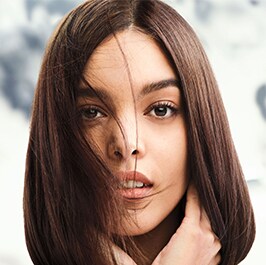 woman with brown straight har with foliage in the background