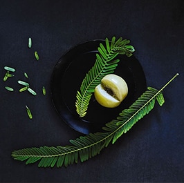 green ingredients layerd onto a black plate on top of a dark background